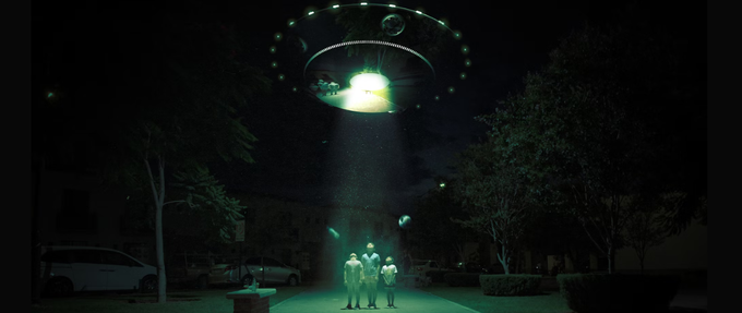 three children looking up into the green light of an alien space ship
