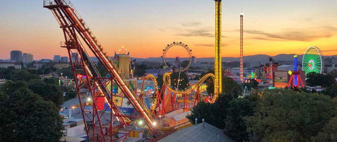 a picture of a lit up amusement park at sunset from bird's eye view