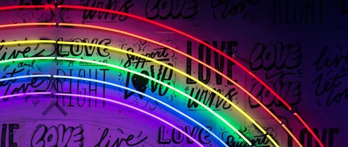neon rainbow lights with "love is love" messages on the wall behind it