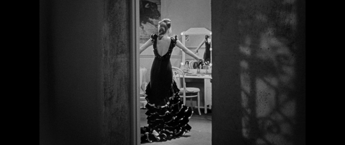 still shot from the leopard man of woman standing in front of a mirror in a long black dress