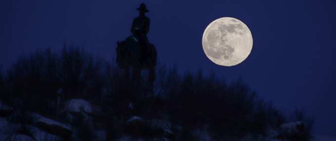 cowboy on a horse on a mountain by the light of the moon